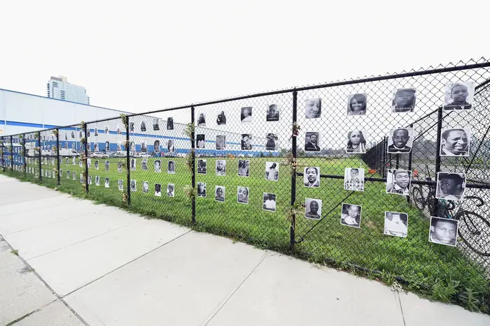 "Say Their Names" memorial in Brooklyn, featuring photos of victims of police violence along a chain link fence.